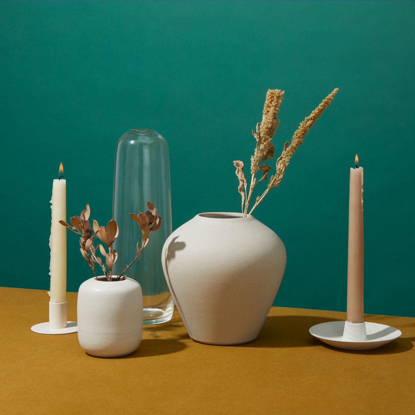 Grouping of vases, candle holders and candles with flowers.