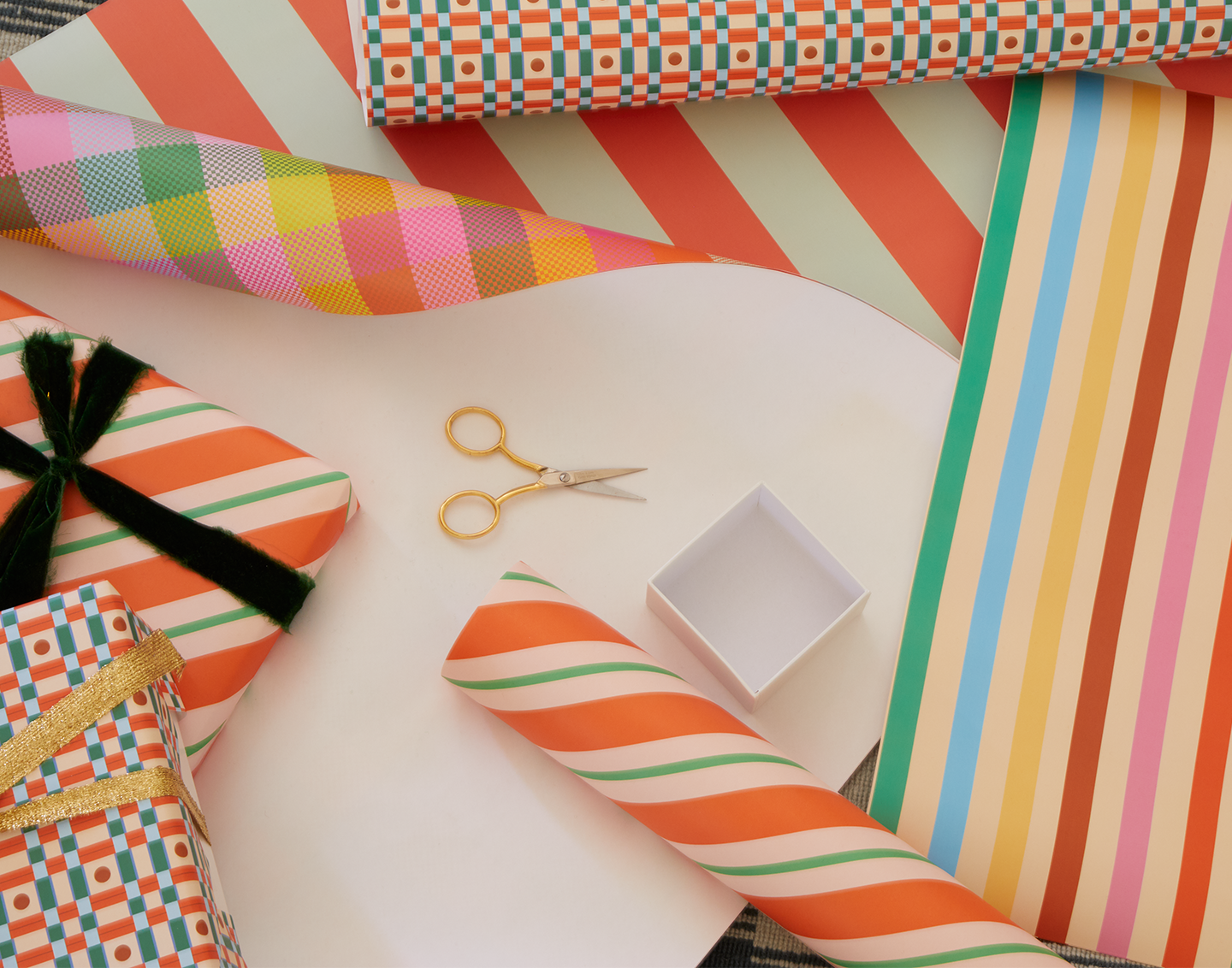 Colorful gift wrap with scissors and a box on a white surface