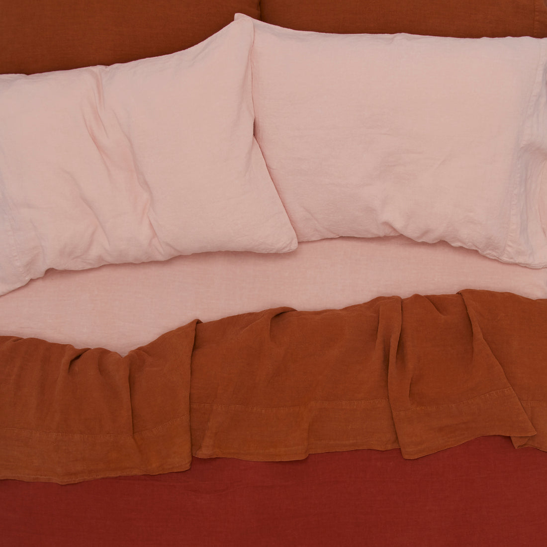 overhead of a blush/rust/terracotta Simple Linen bed.