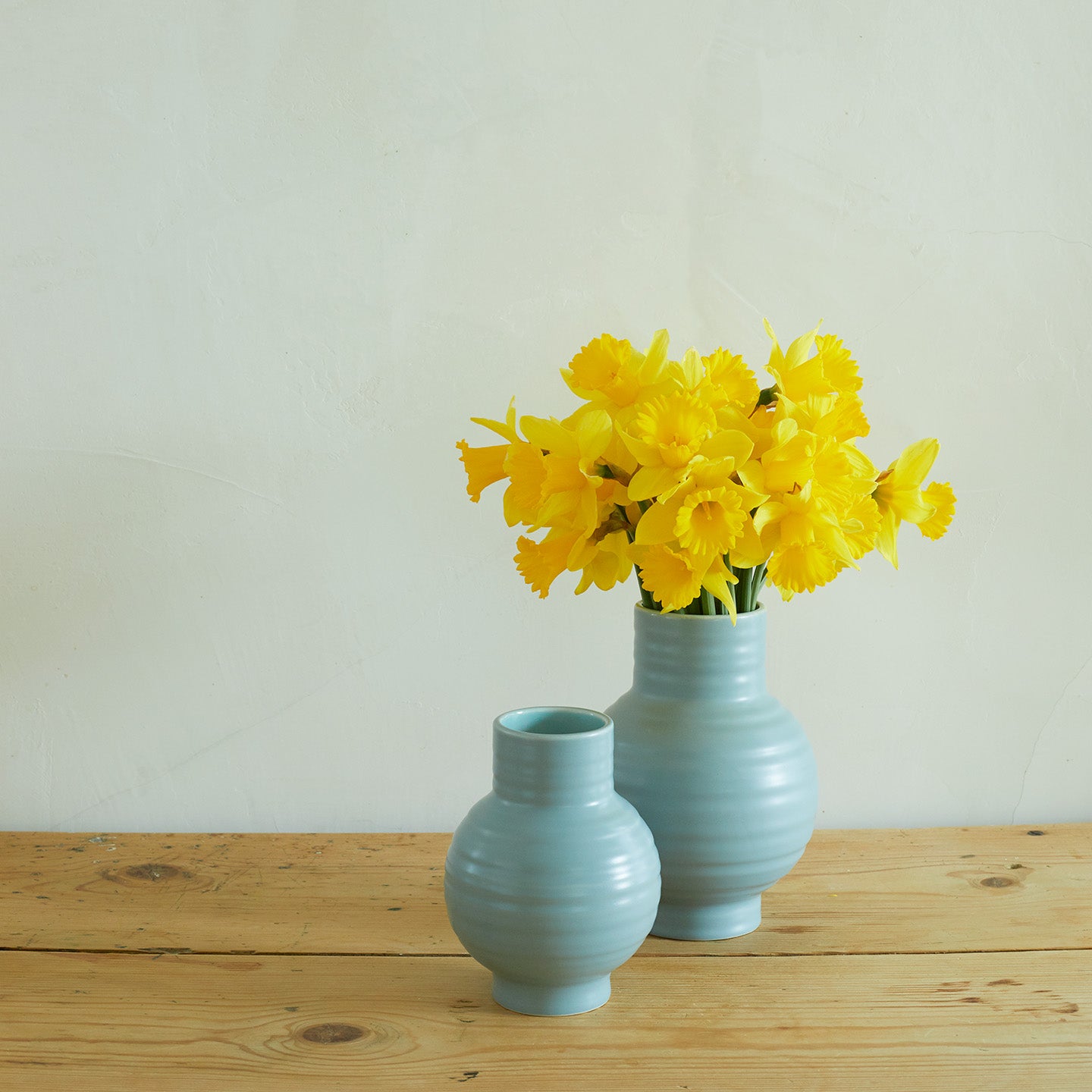 Essential Ceramic Vase in Sky on wood countertop with daffodils.