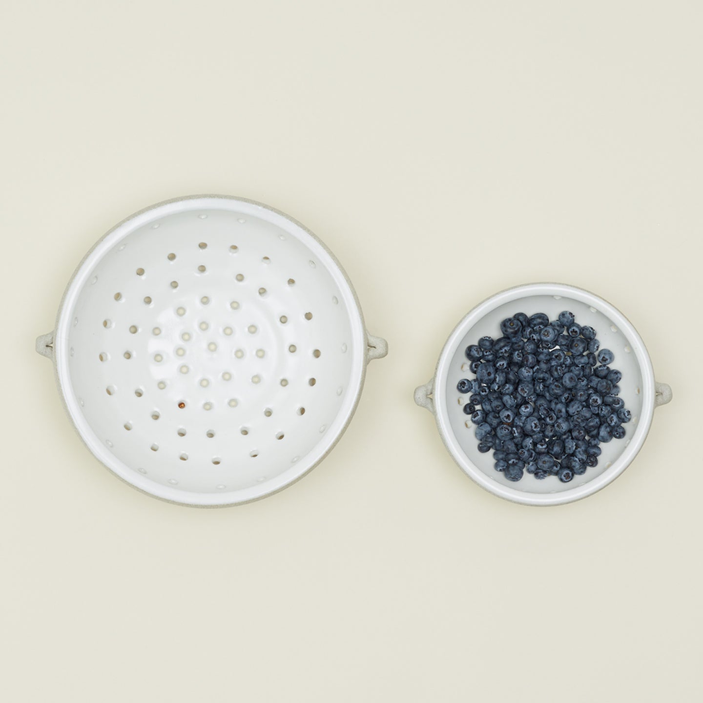 Overhead view of large and small colander with blueberries