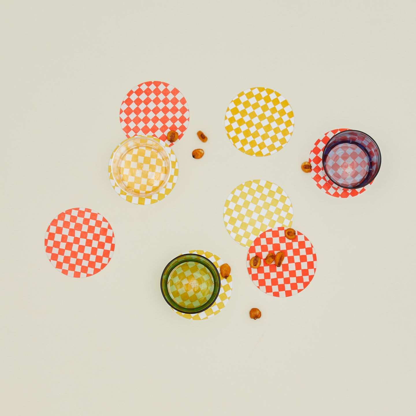Set of eight reusable checkered paper coasters with glassware and snacks.