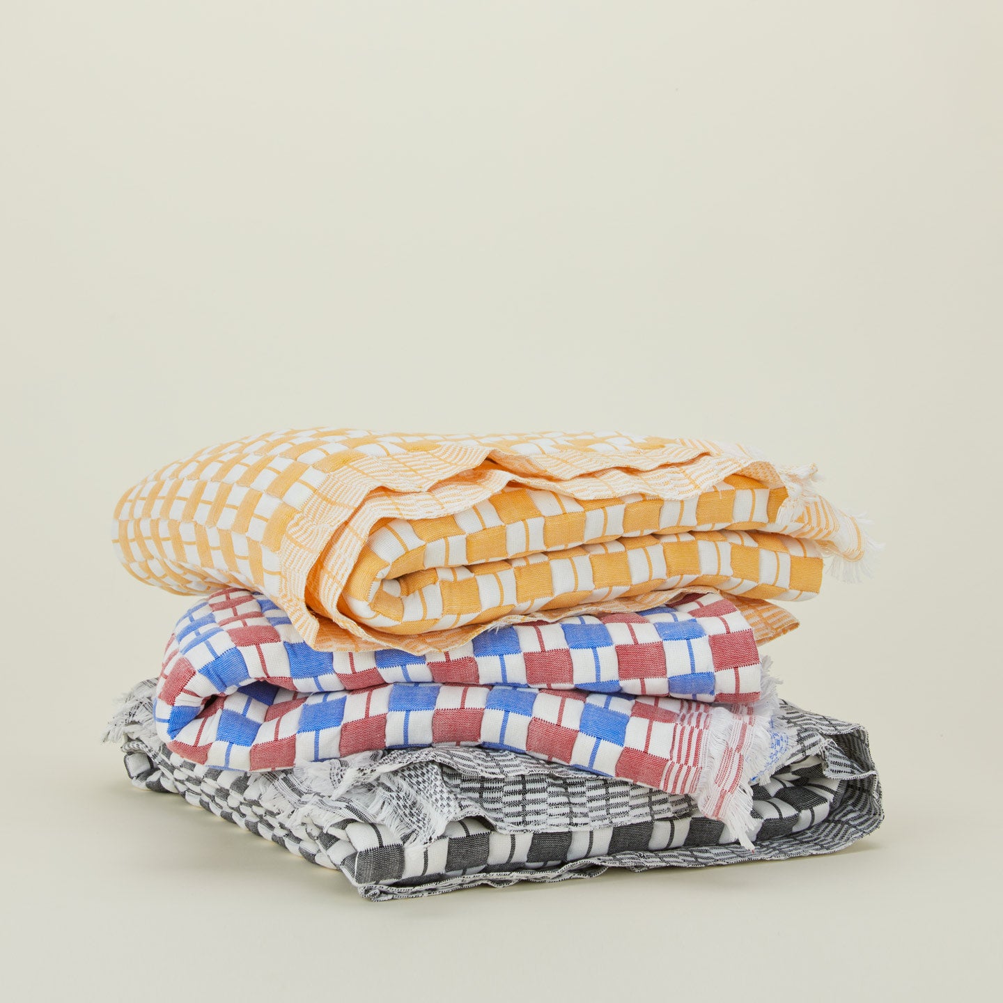 Folded stack of quilted checkered throws in various colors.