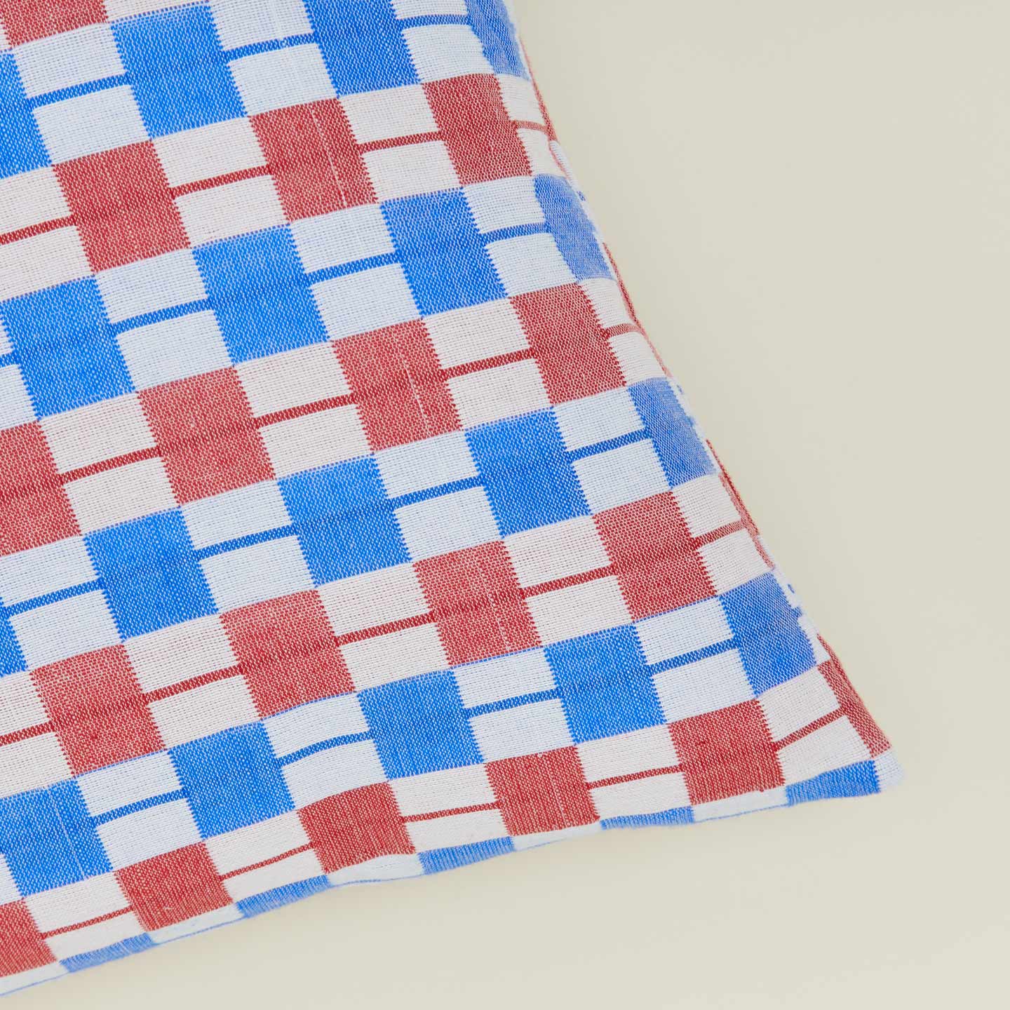 Corner detail of quilted checkered pillow in red and blue.
