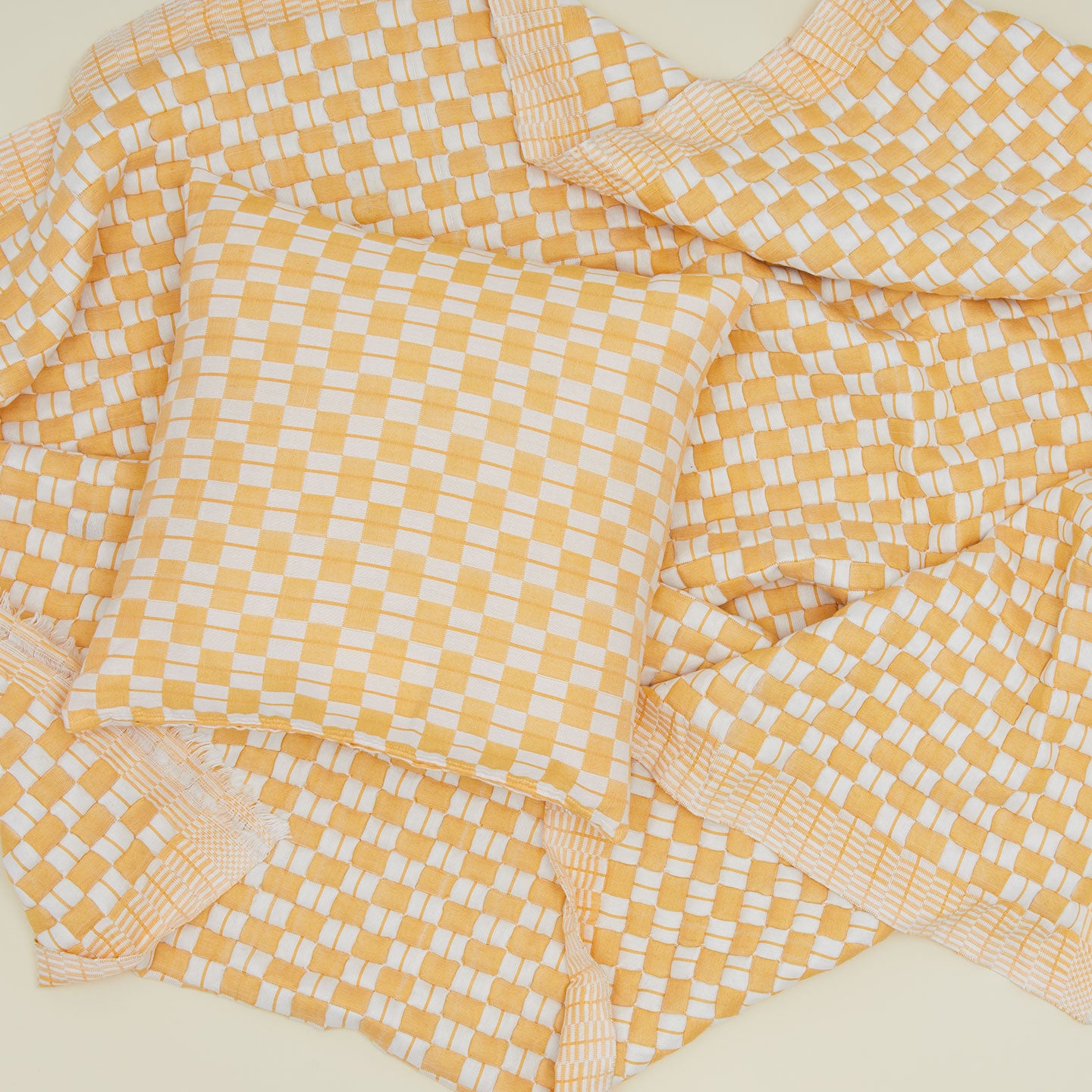 Quilted checkered pillow and throw in yellow and white.
