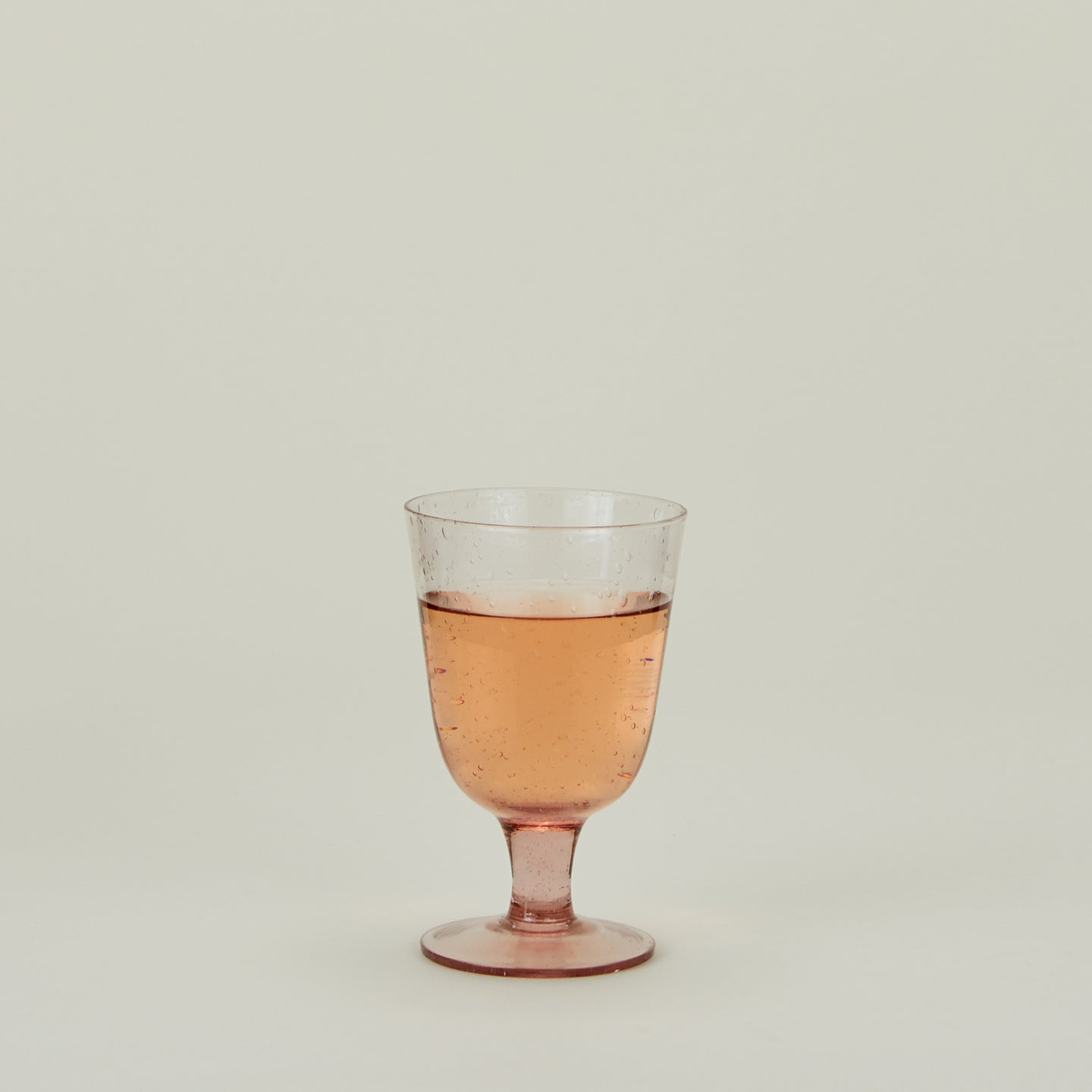 Stemmed Wine Glass in Blush, filled with water.