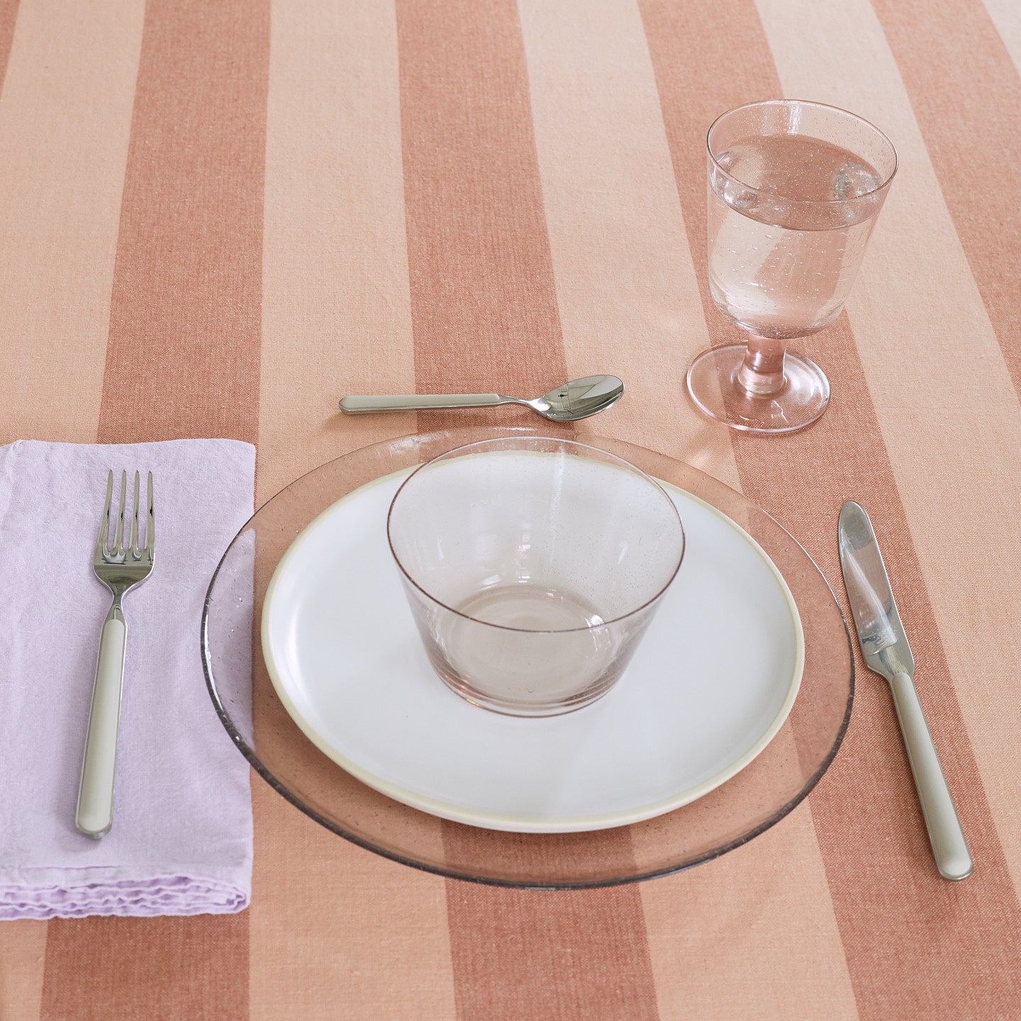 Placesetting with Stemmed Wine Glass in Blush on pink striped tablecloth.