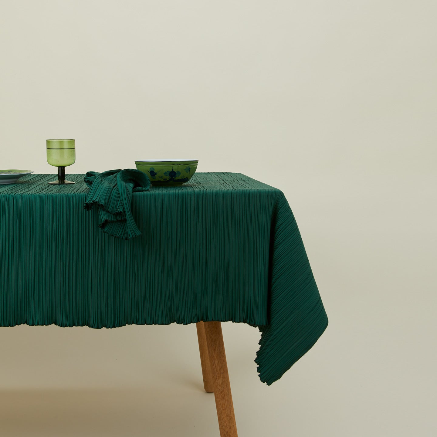 Cahaya pleated tablecloth in olive on table with bowld napkin, plate, and stemware