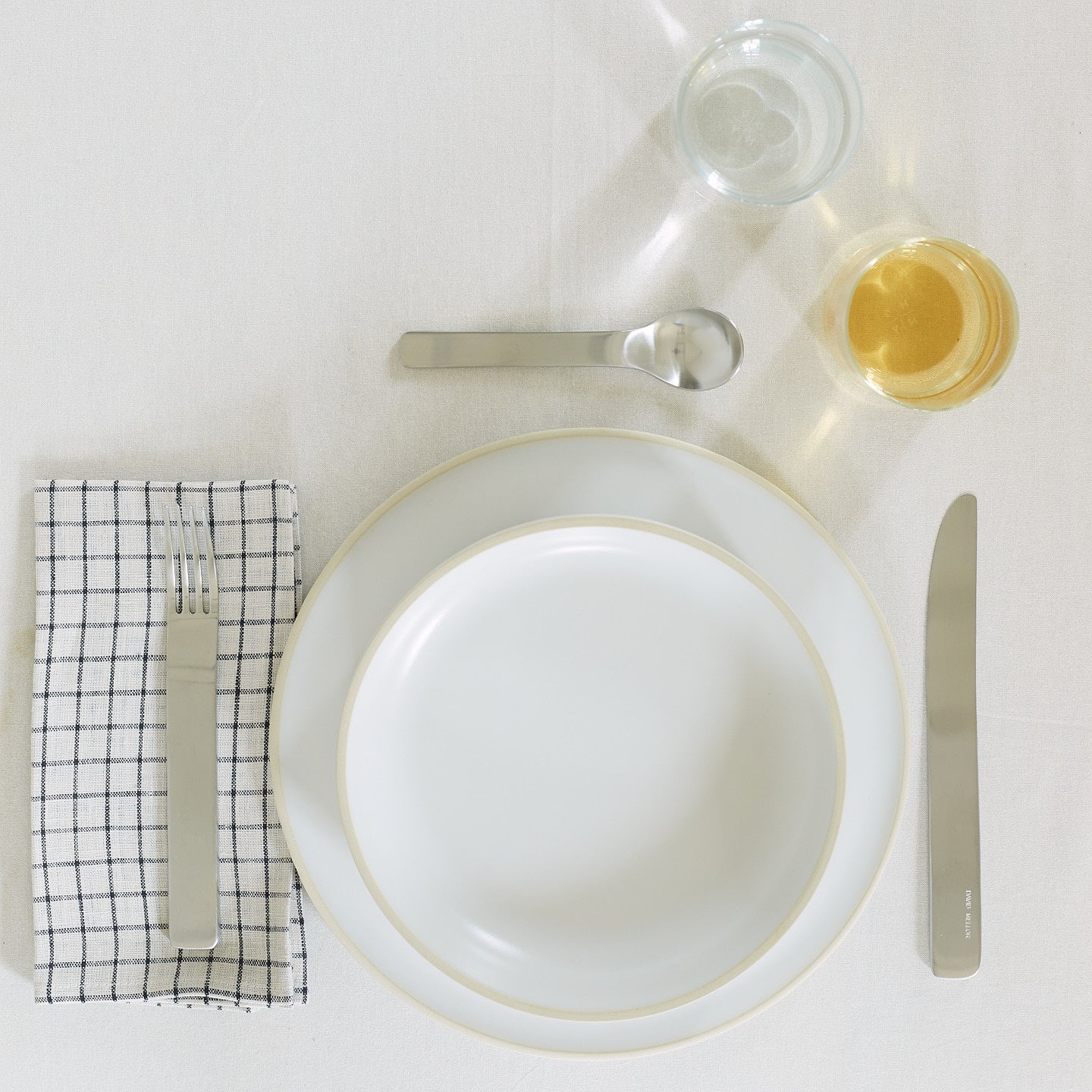 Placesetting with Checked Linen Napkin on white tablecloth.