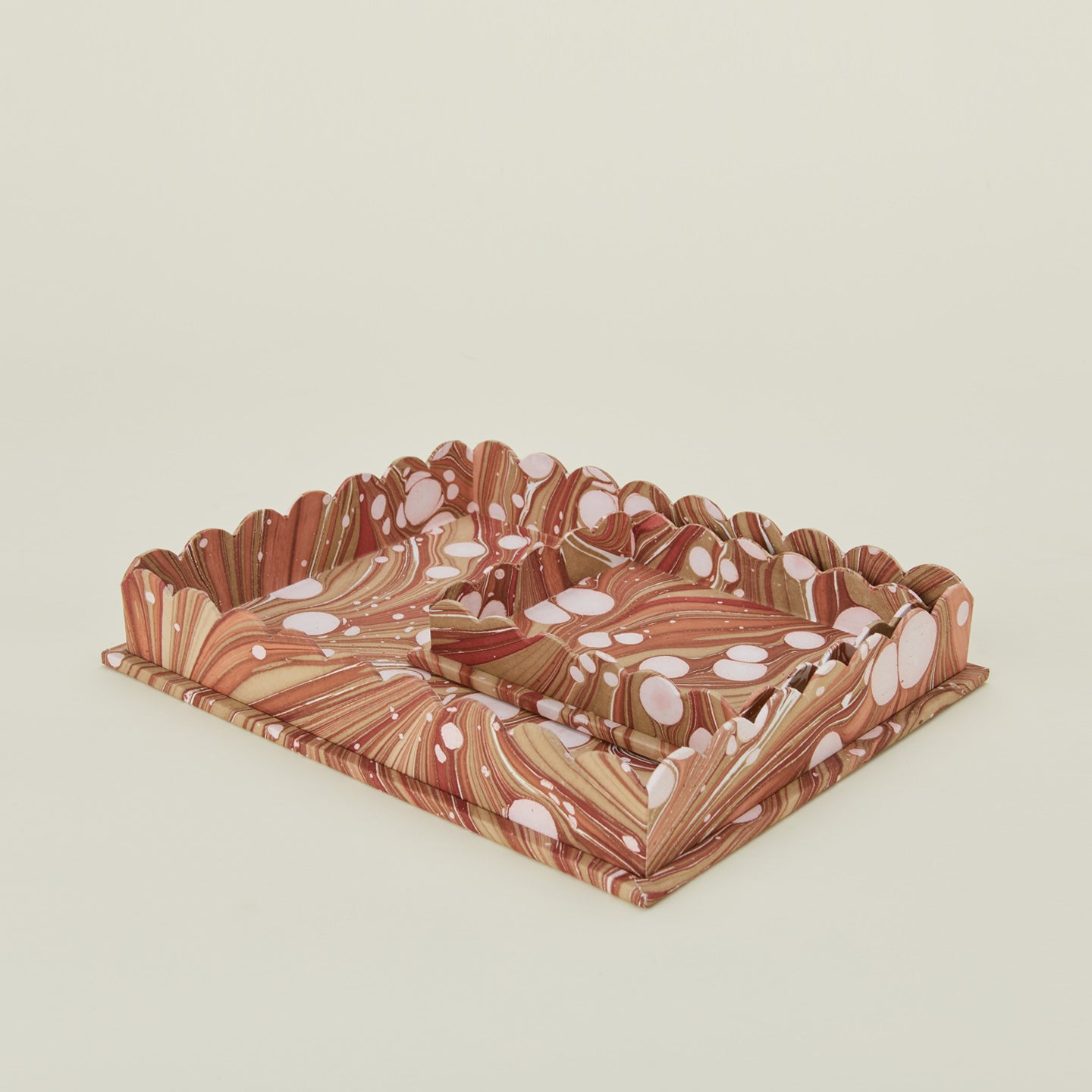 Detail view of two scalloped marbled trays in mocha.