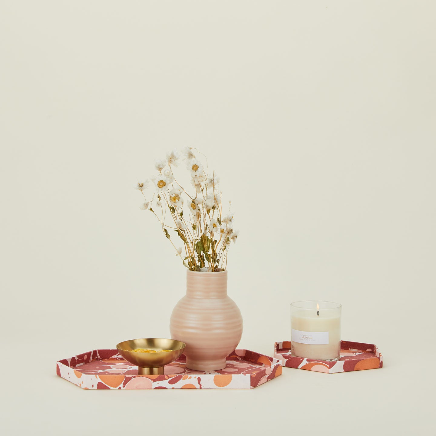 Set of two hexagon marbled trays in warm tones with vase, footed bowl, and scented candle.