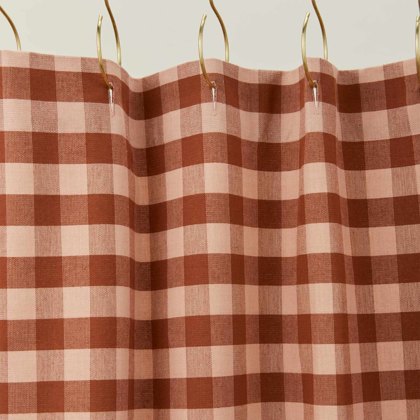 Gingham shower curtain in blush/terracotta on gold curtain hooks