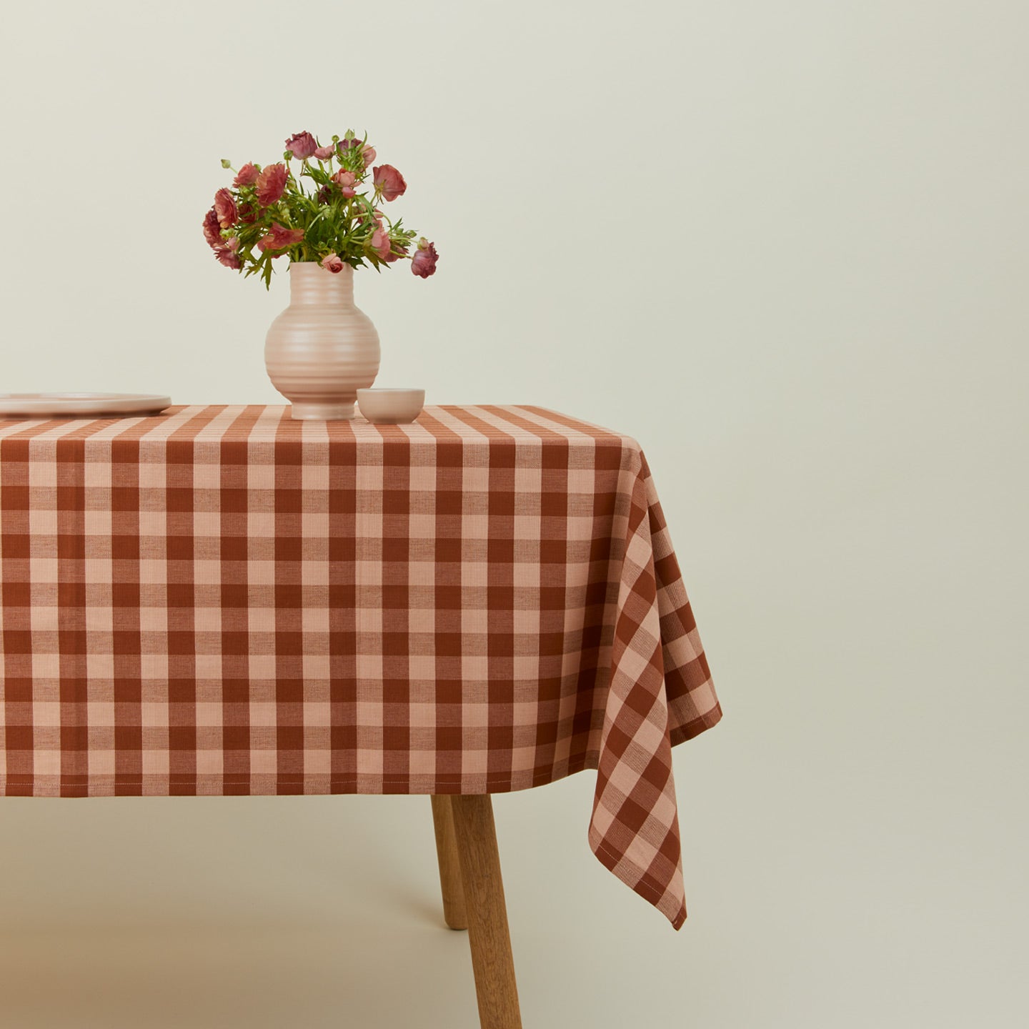 Essential Gingham tablecloth in blush/terracotta on a table with florals.