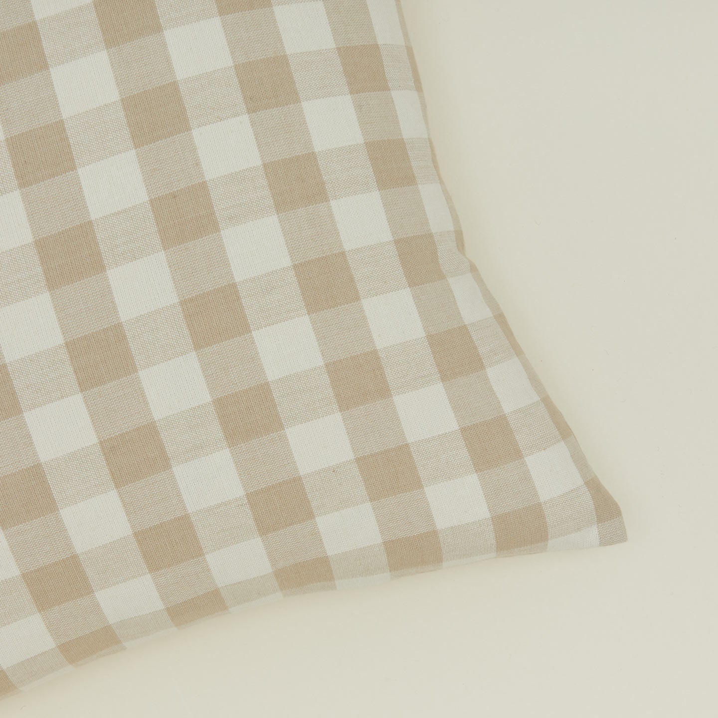 Close up view of gingham square pillow in ivory/flax