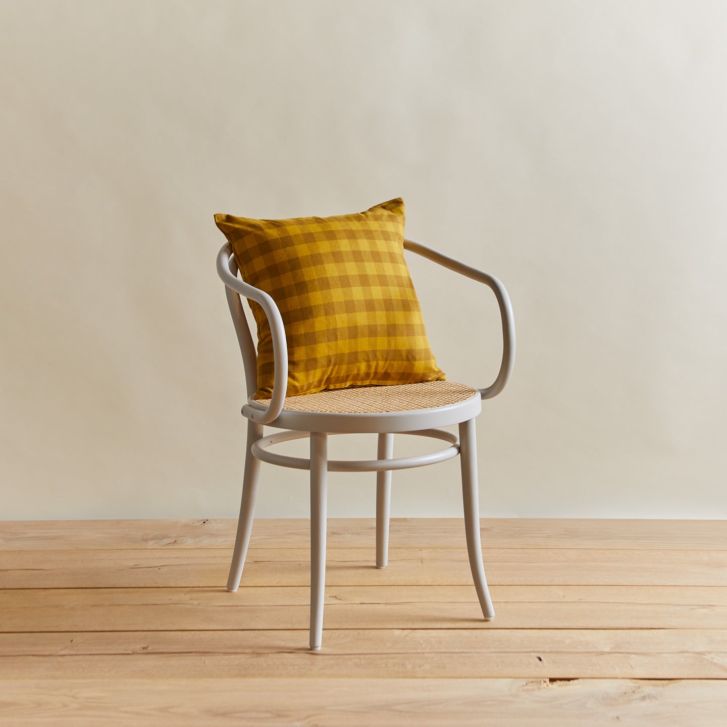 Essential gingham pillow in mustard/bronze on chair