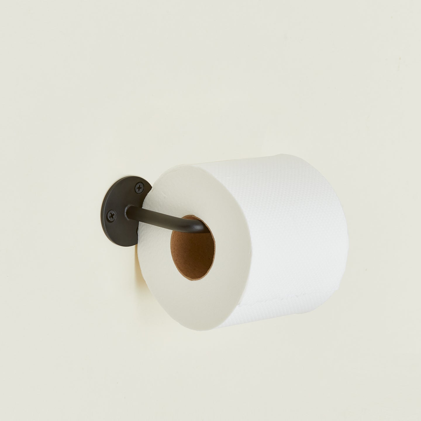 Toilet paper holder in Black with a roll of toilet paper.