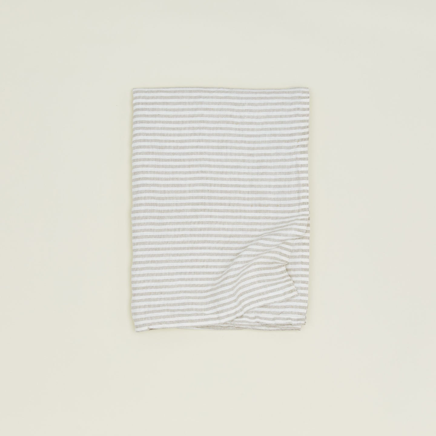A folded chambray linen throw with white stripes.