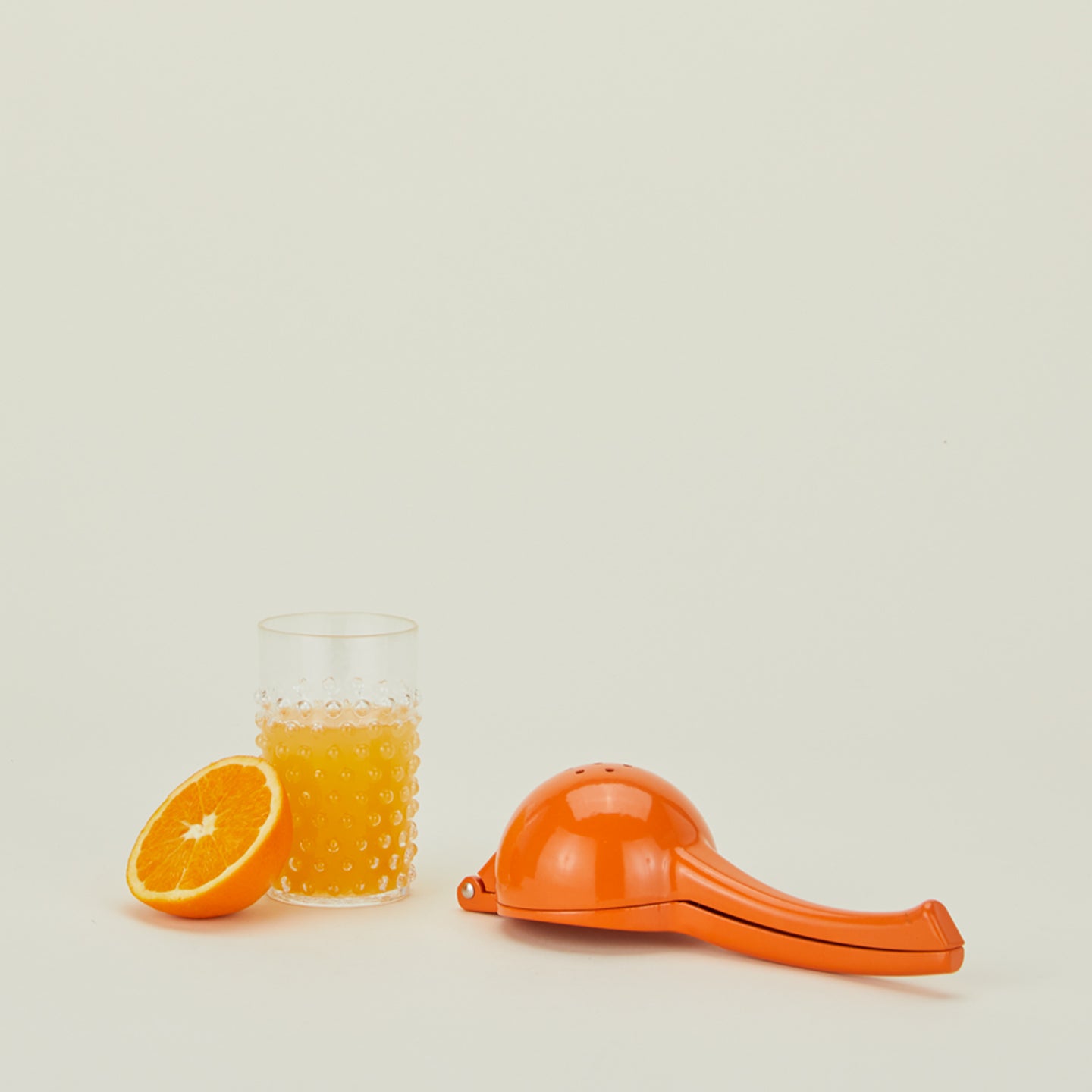Fox Run orange juicer with orange, and orange juice in glass tumbler