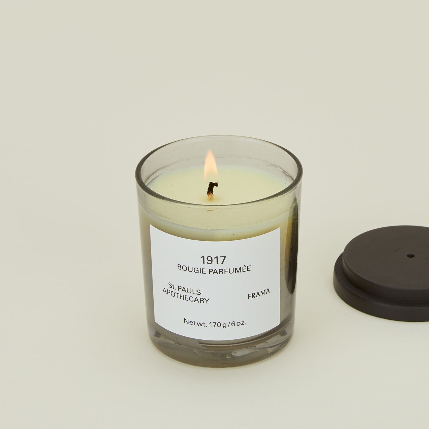 A close up of a lit wax candle with the scent 1917.