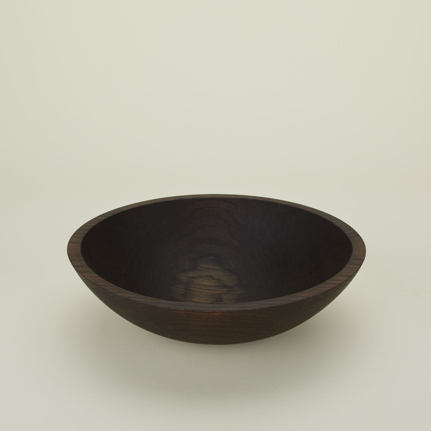 A close up  of a 15” ebonized oak  wood bowl.