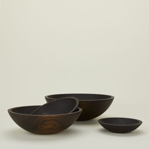 A group of ebonized oak wood bowls in four sizes.