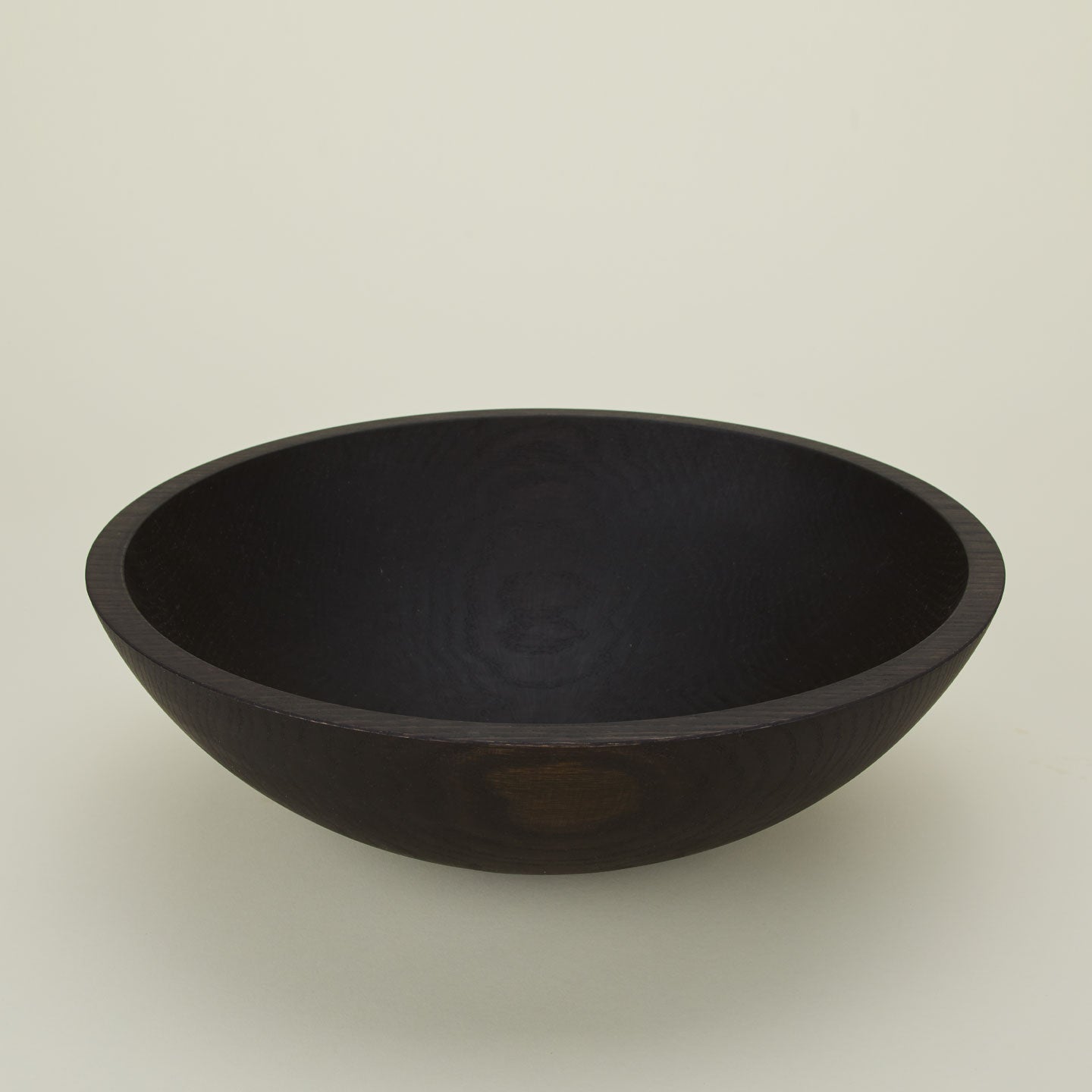 A close up  of a 17” ebonized oak  wood bowl.