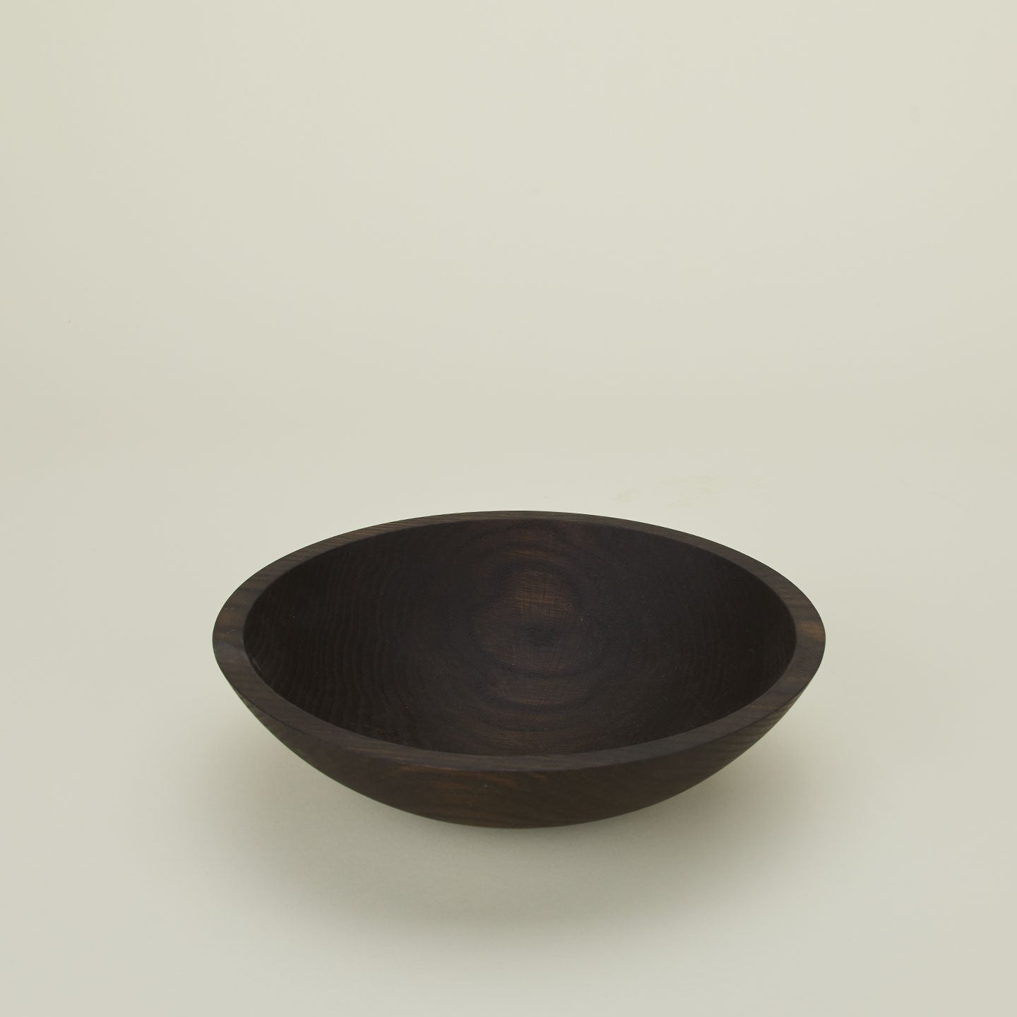 A close up  of a 12” ebonized oak  wood bowl.