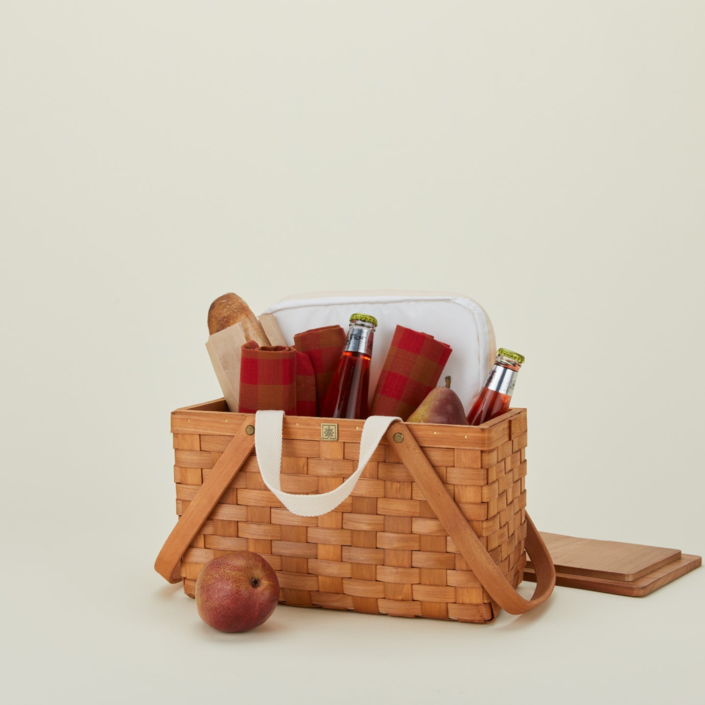 Picnic basket with drinks, bread, apples and plates