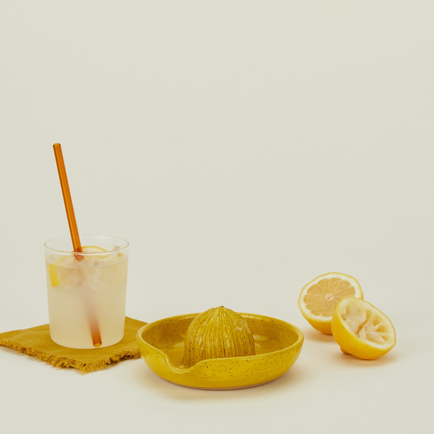 Stoneware citrus juicer in Yellow with lemon and juice.
