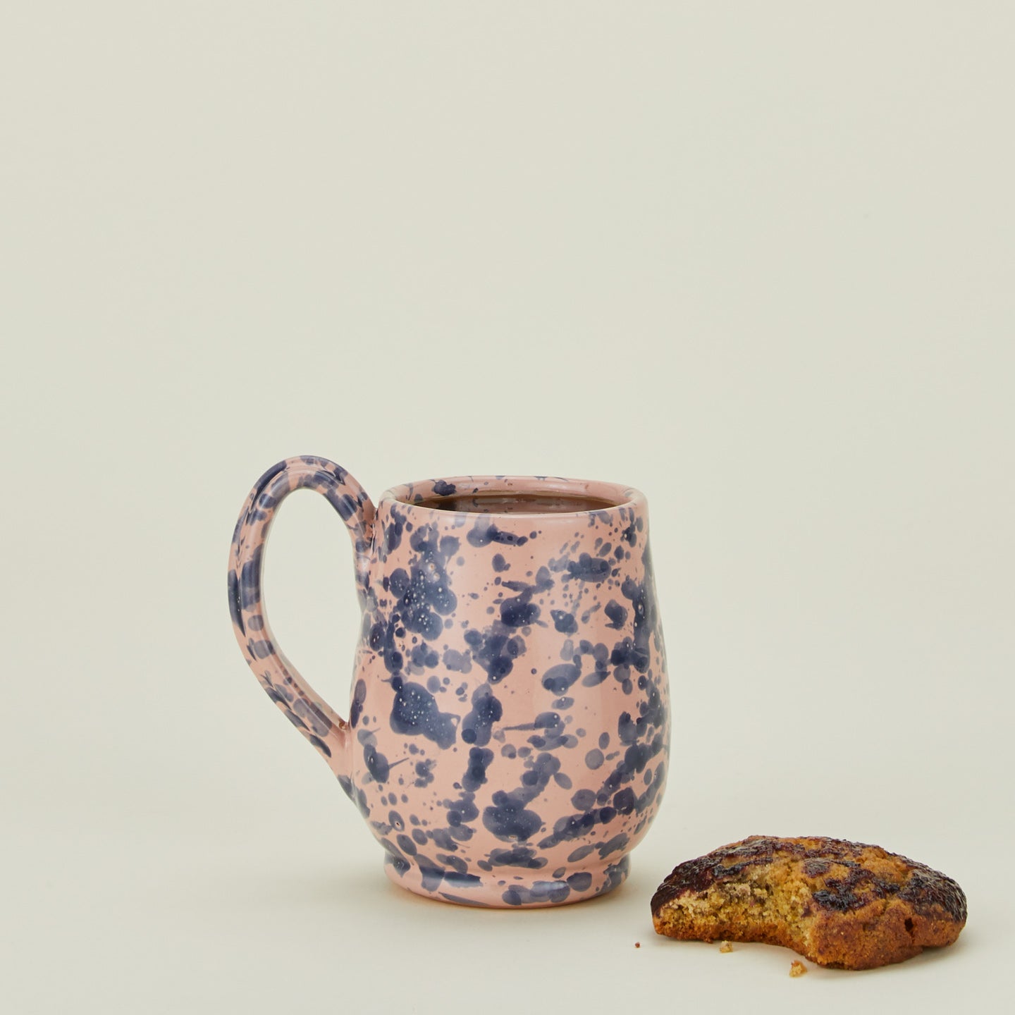 Splatter mug in pink and blue with coffee and cookie