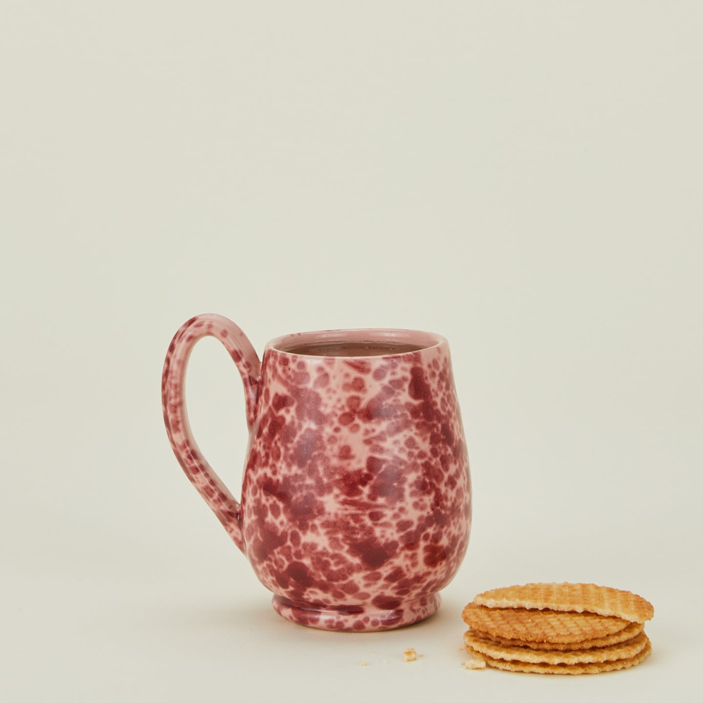 Splatter mug in pink and red with biscuits and coffee