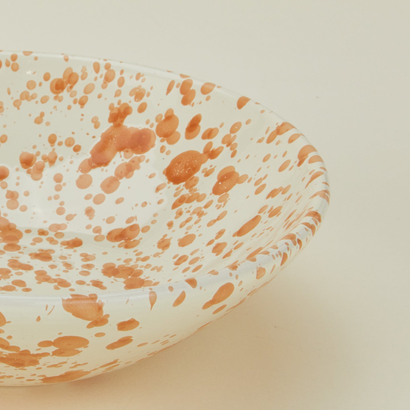 Close up view of Splatter low bowl in tan and ivory
