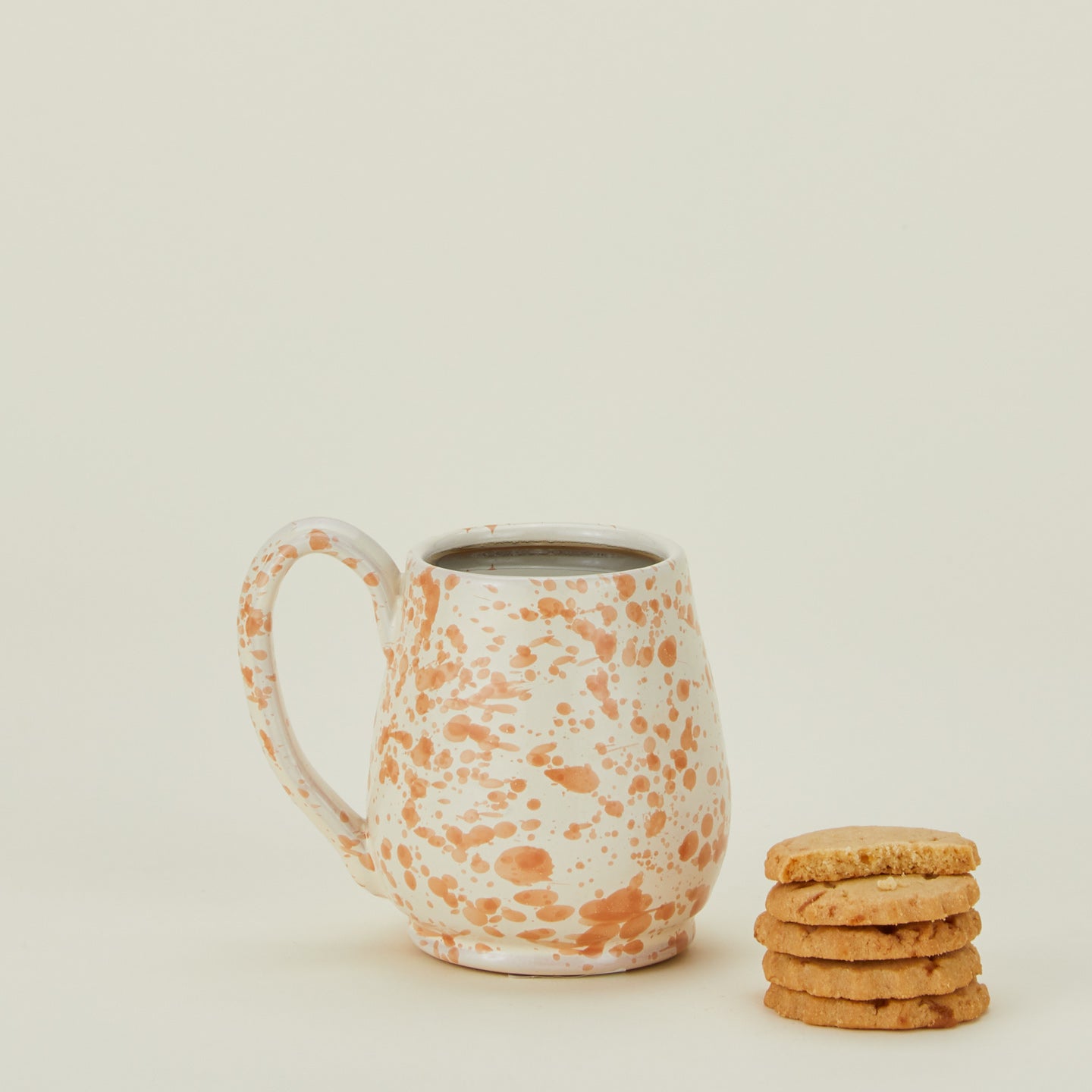 Splatter mug in tan and ivory with coffee and cookies