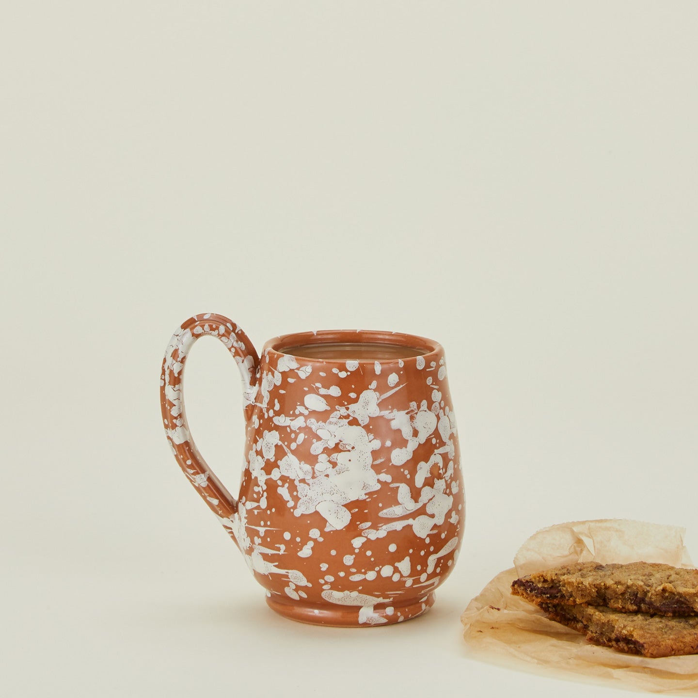 Splatter mug in terracotta and ivory with cookie and coffee