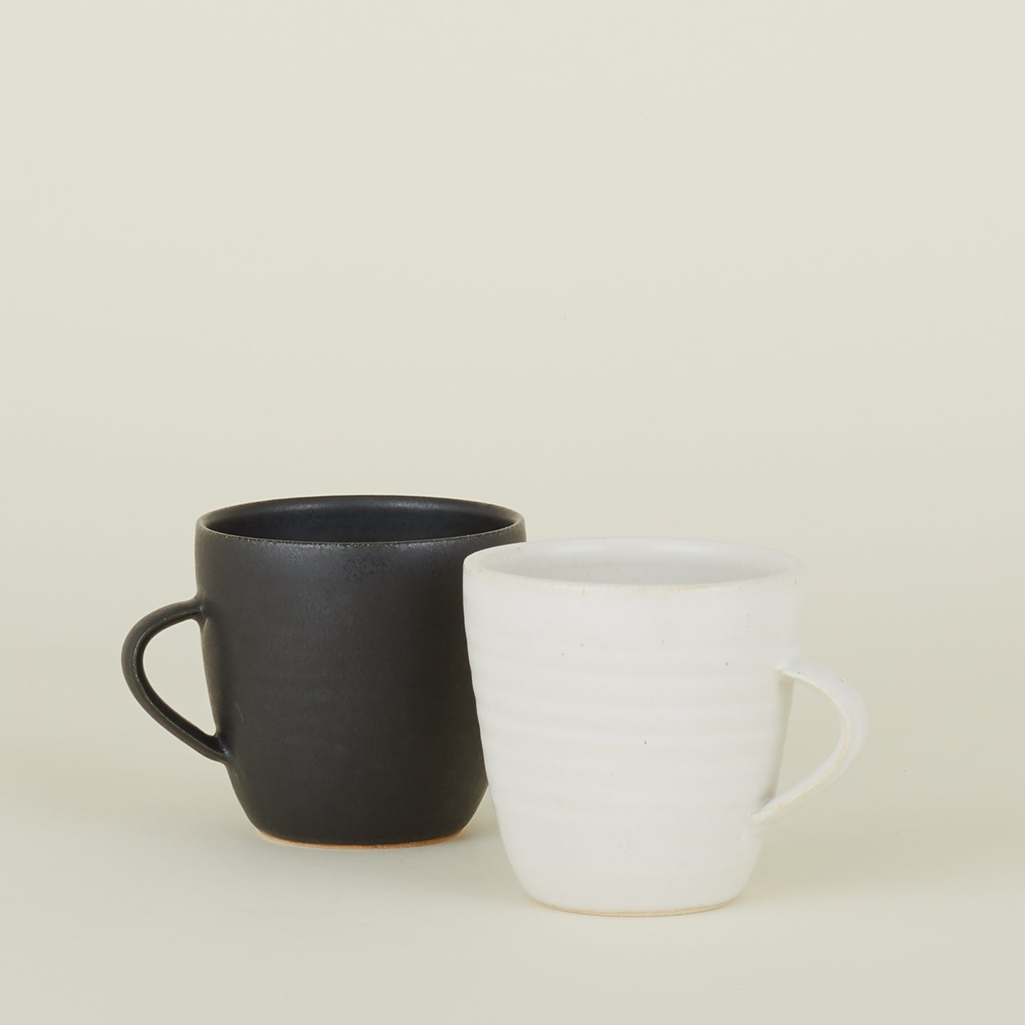 Two Stoneware Mugs, one in Black and one in Eggshell.