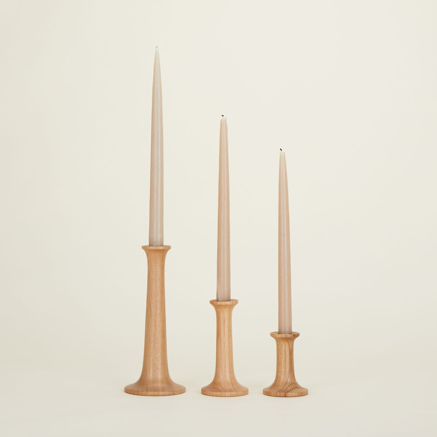 three taper candles in wood holders 