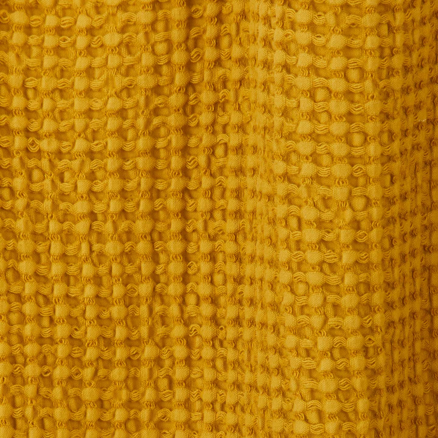 Close up view of simple waffle shower curtain in mustard