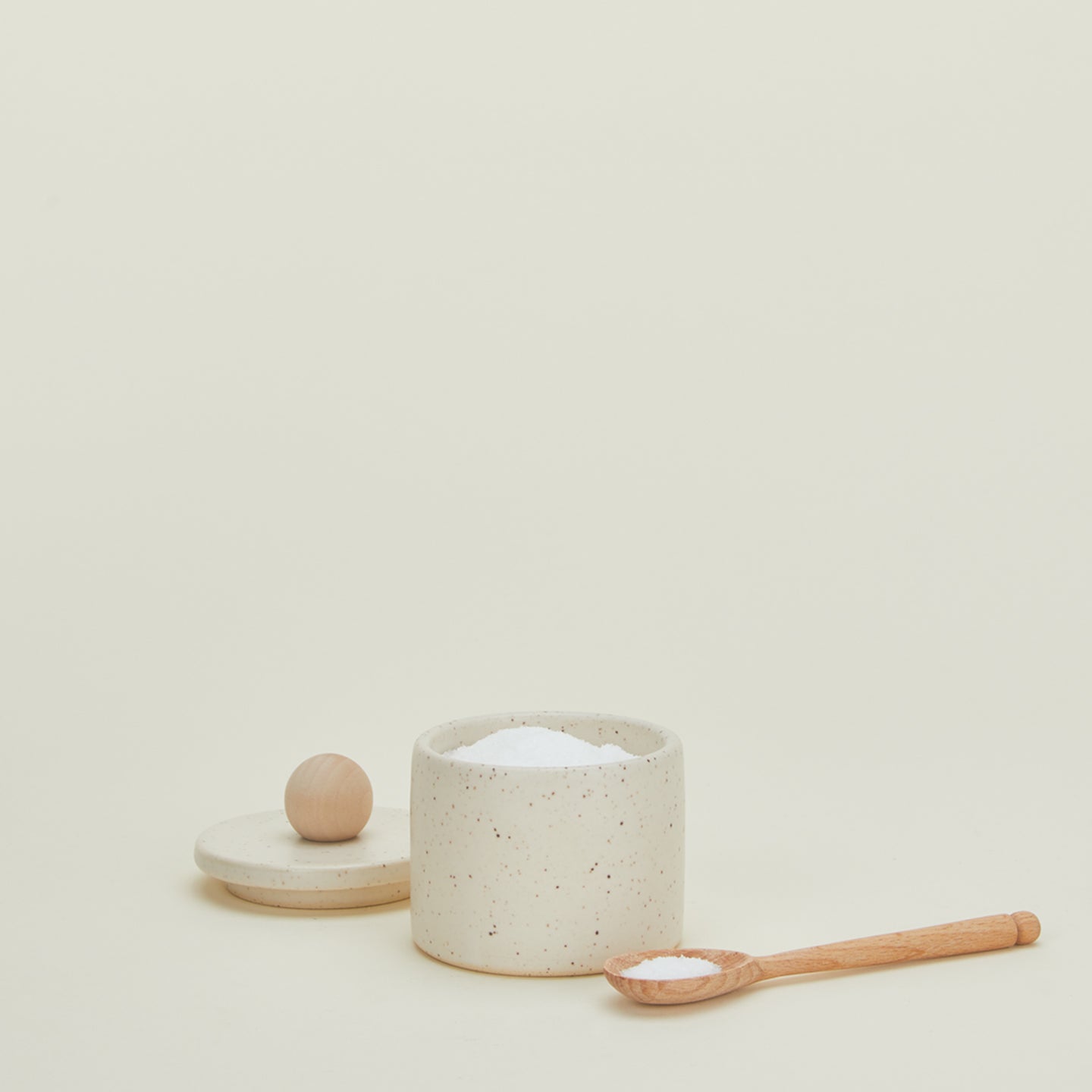 Speckled salt cellar with lid off and wooden spoon
