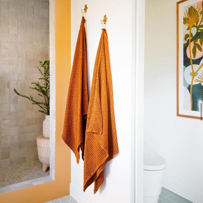 HNY Simple Waffle towels in Terracotta hanging on a wall.