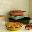 Kitchen counter vignette with stack of bakeware and pie in pie dish.