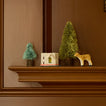 Reindeer paper mache ornament on mantle with bottlebrush trees