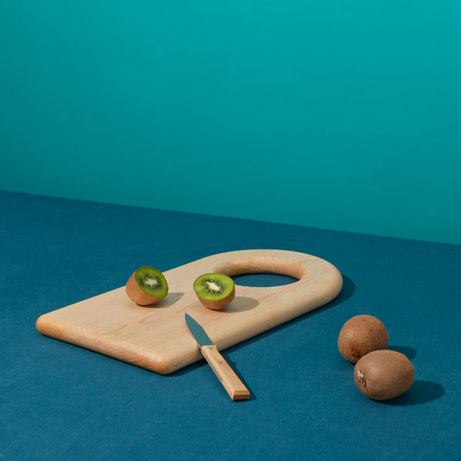 cutting board and knife styled with kiwis on blue background