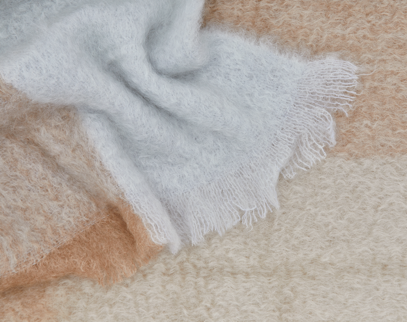 Close-up of a plaid textured mohair throw with fringe.