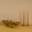A trio of footed bowls and pair of candle holders, all in Mustard, with honey taper candles.