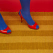 Red high-heeled shoes with blue toes Essential Floor Mat in Mustard with red background.
