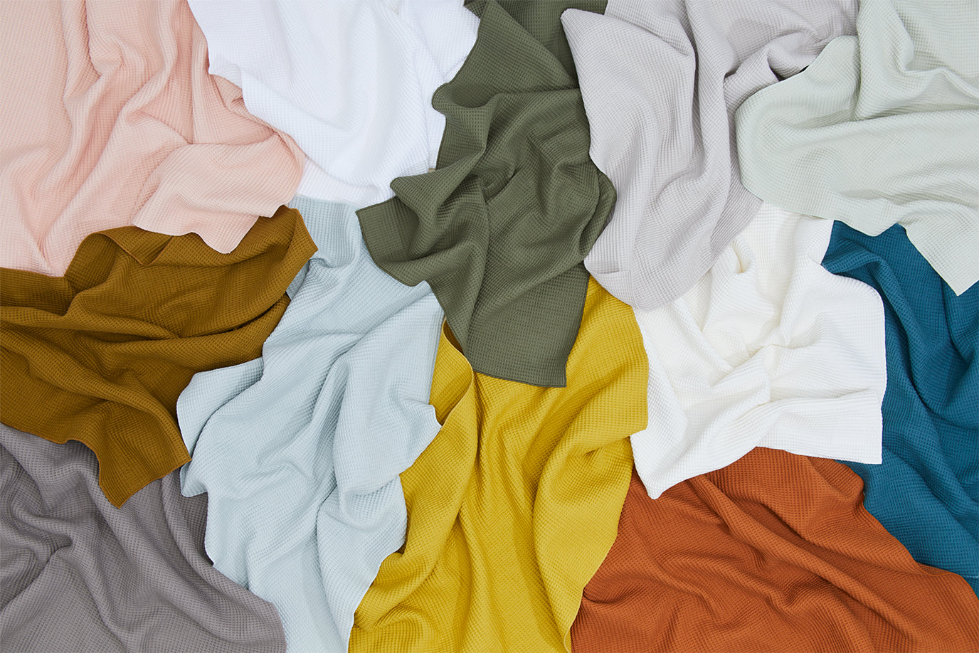 A pile of Essential Waffle Dish Towels in a variety of colors.