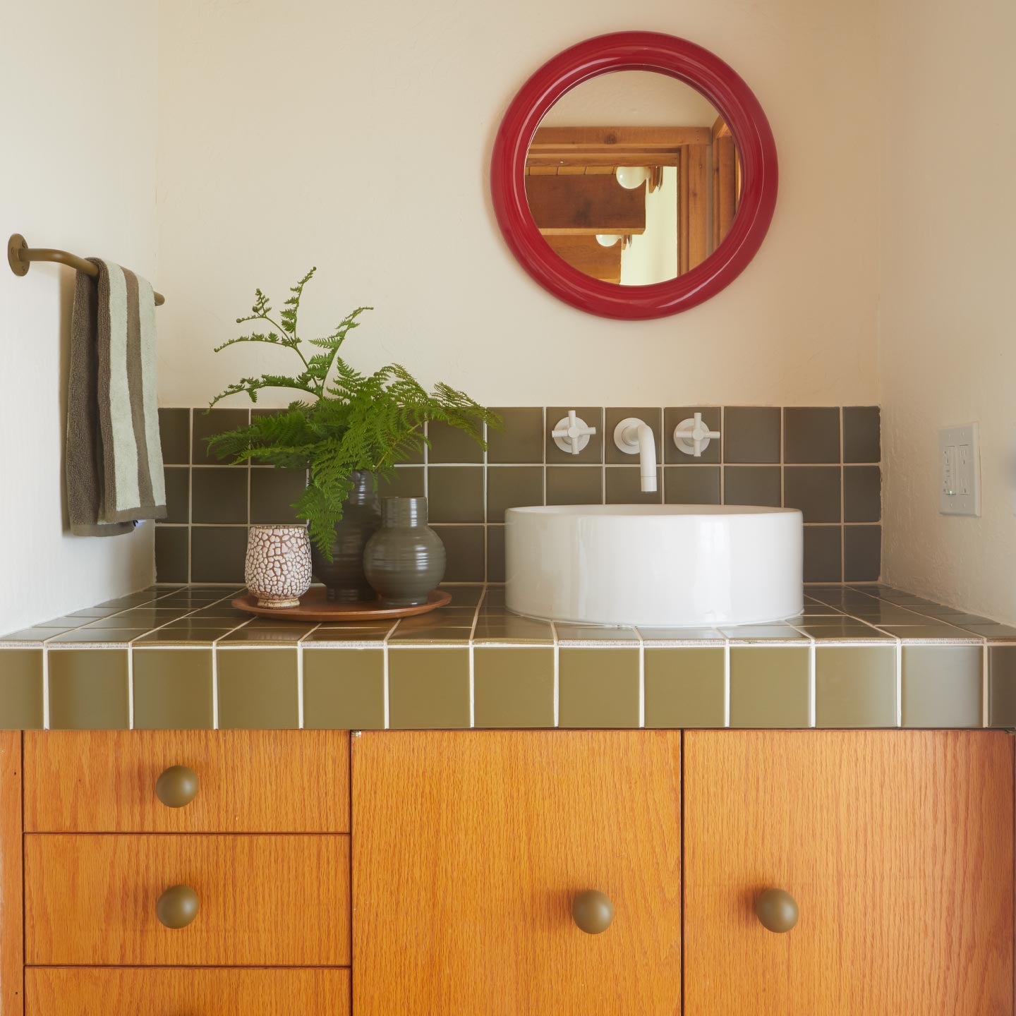 Bathroom countertop with vases and towel hanging on wall.