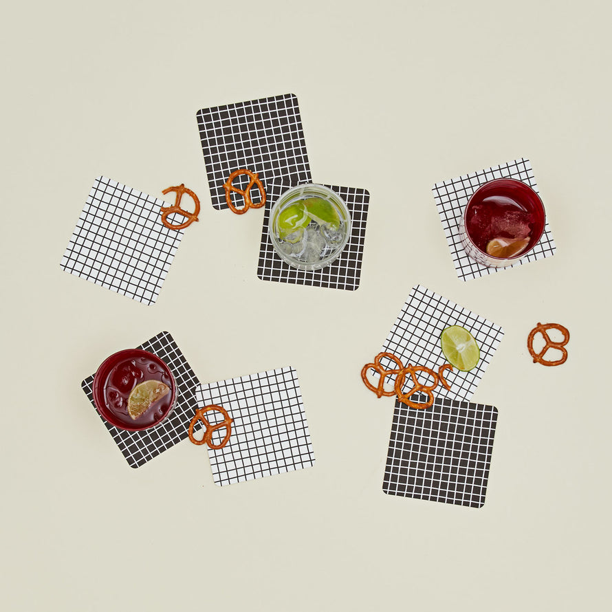 Set of eight reusable gridded paper coasters with glassware and snacks.