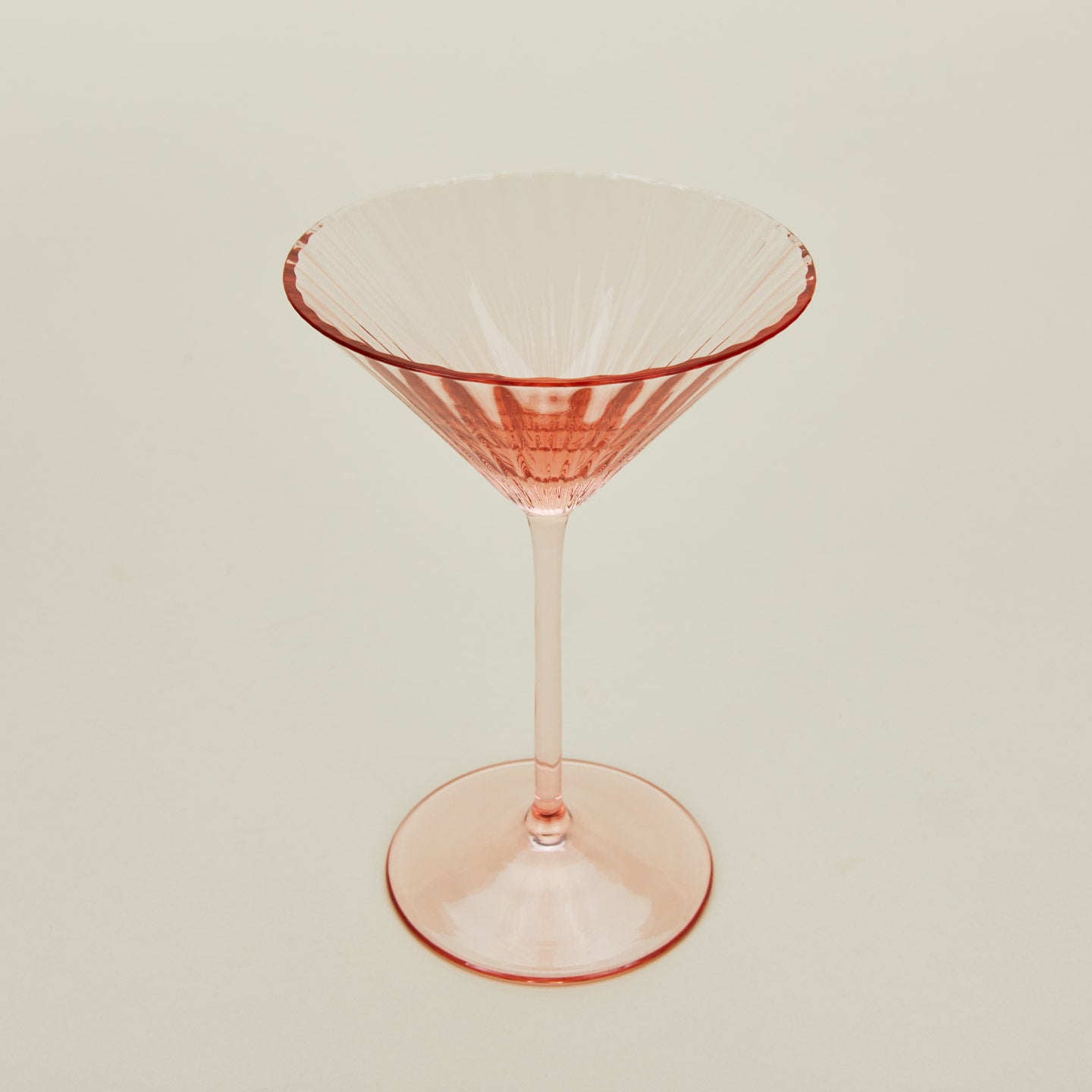 Three-quarter angle of ribbed blush martini glass.