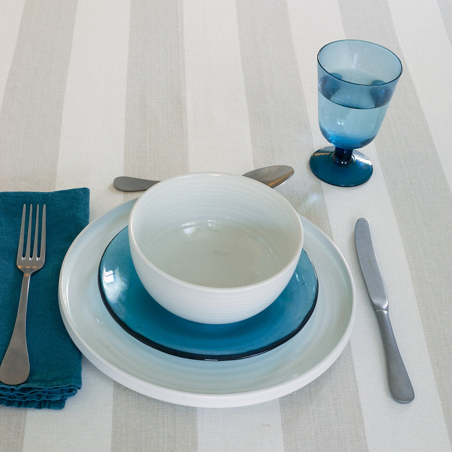 Placesetting with Stemmed Wine Glass in Peacock on ivory striped tablecloth.